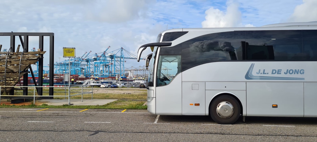 Grijze bus bij de Parkeerplaats van Futureland op de tweede Maasvlakte voor een prachtige foto met de blauwe kranen van de Maersk. Havens